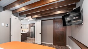 Een slaapkamer met een oranje sprei, een houten plafond, een schuifdeur en een bevestigde televisie.