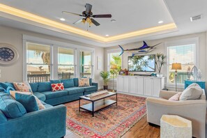 A spacious living room with a blue sofa, a coffee table, and a ceiling fan.