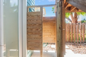 A wooden gate leading to a patio area with a wooden fence and a palm tree in the background. - Sun of a Beach by Silver Sands Vacation Rentals (Port Aransas)