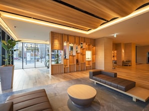 Un vestíbulo moderno con paneles de madera, zonas de estar y un mostrador de recepción.