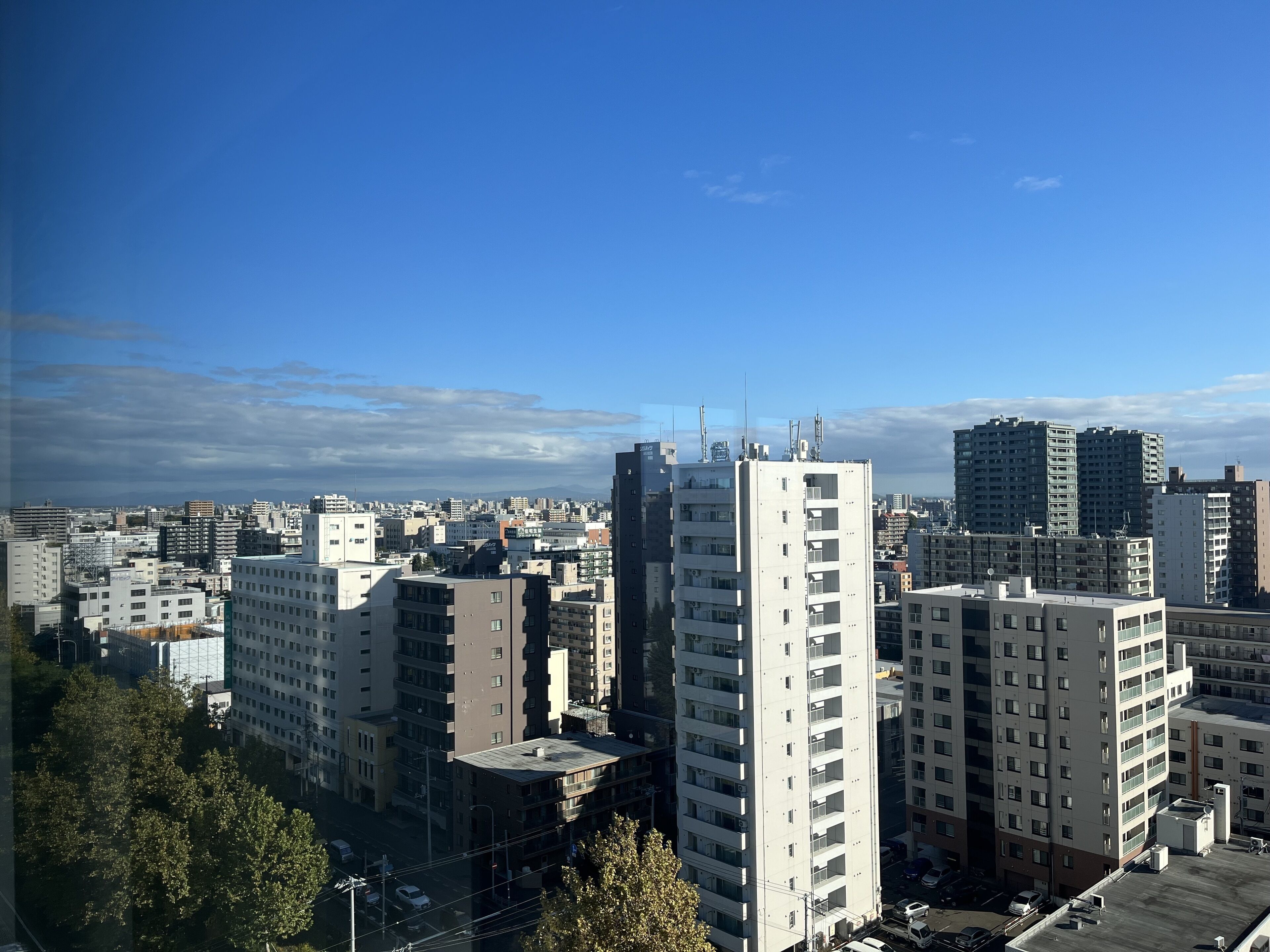 A cityscape with multiple high-rise buildings, including a prominent white building with a flat roof and numerous windows.