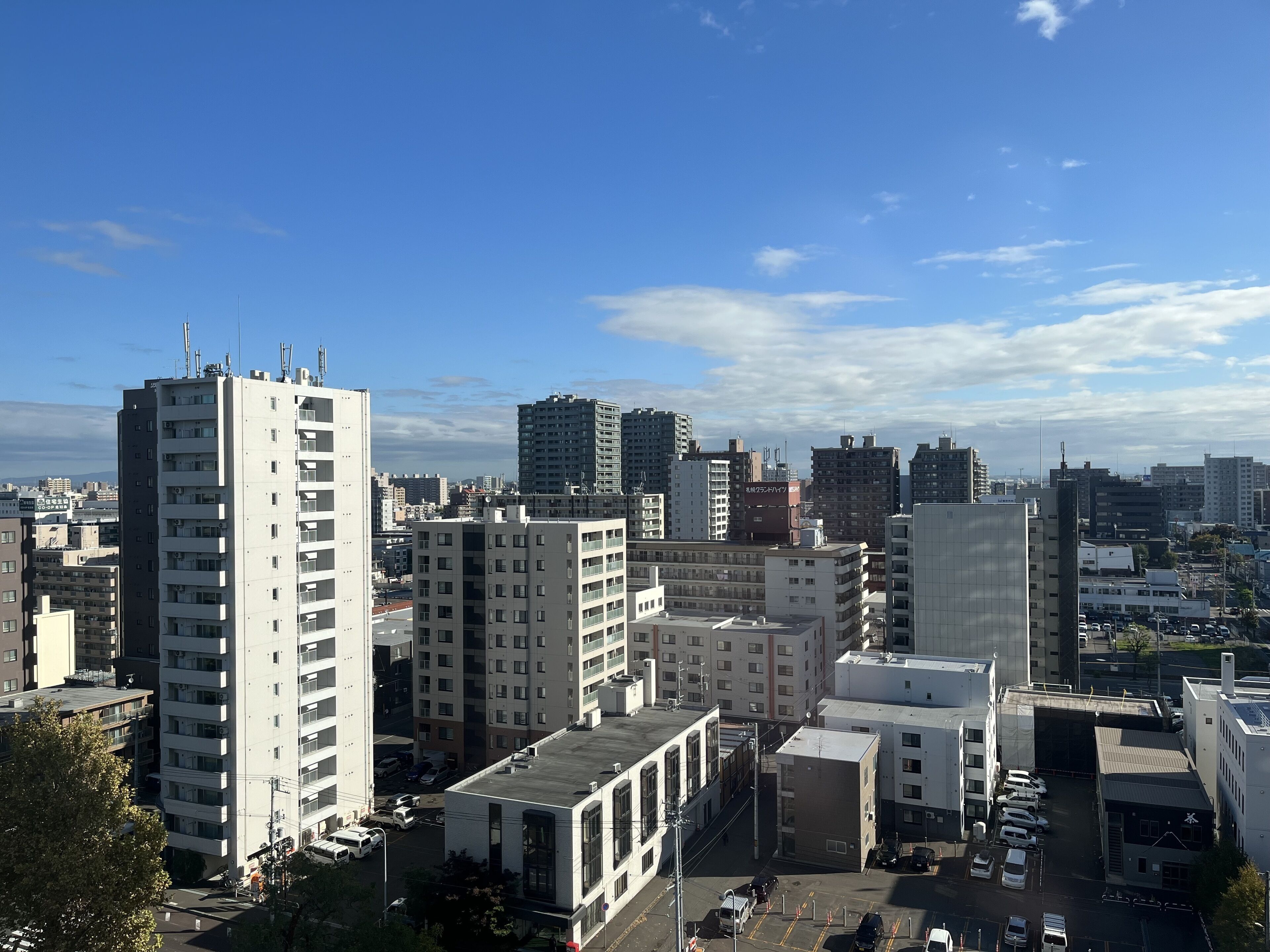 A cityscape with high-rise buildings, a parking area, and a clear sky.
