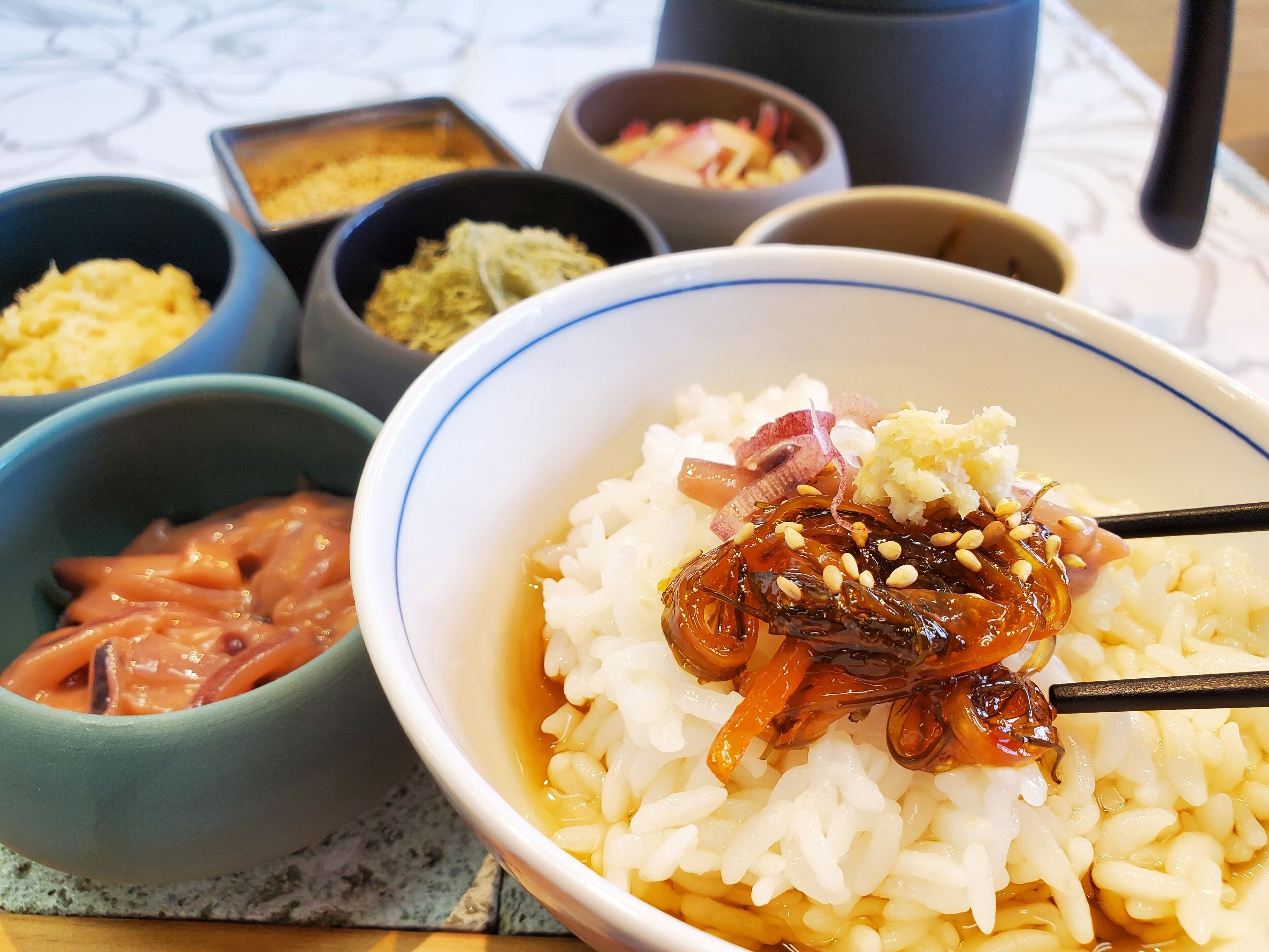 A bowl of rice with toppings, accompanied by various side dishes in separate bowls.