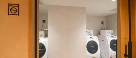 A laundry room with two front-loading washing machines and a control panel.