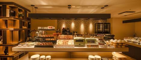 Zona de bufé con diversas opciones de comida y una estación de café.