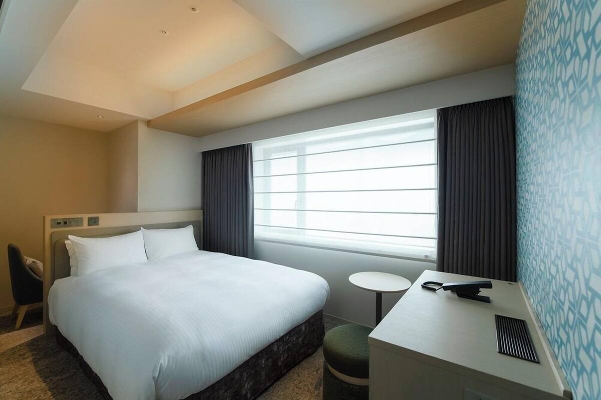Une chambre d’hôtel avec un lit, une table de chevet, une chaise et une petite table ronde.