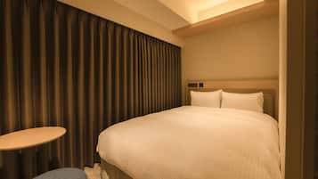 A hotel room with a large bed, a small round table, and a curtain.