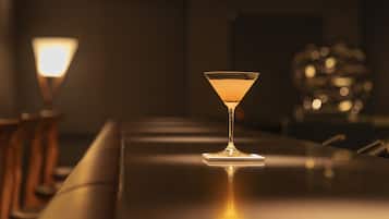 Un bar avec un seul verre à martini posé sur une surface réfléchissante, une lampe et un arrière-plan flou.
