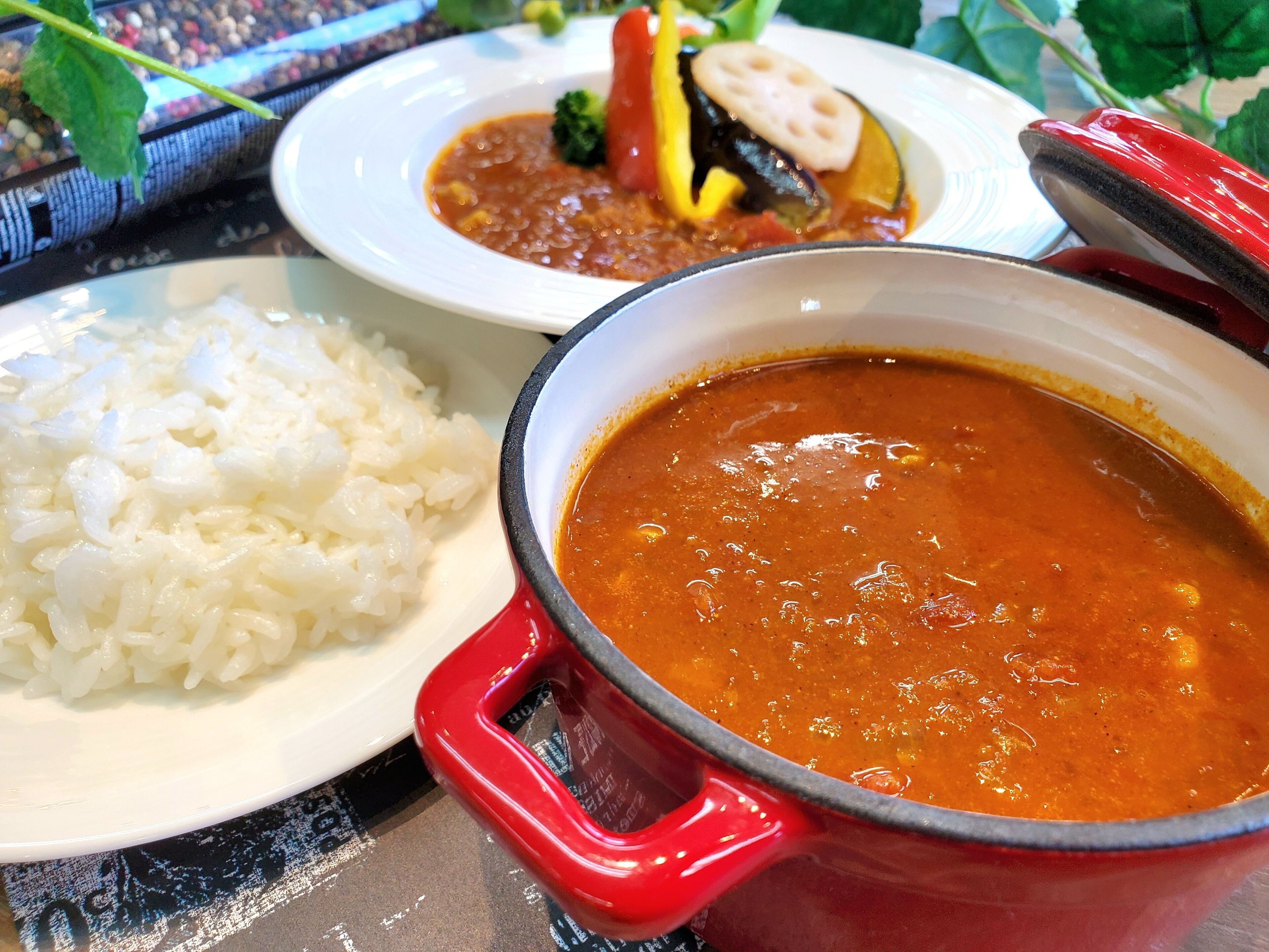 A table with a pot of soup and a plate of rice.