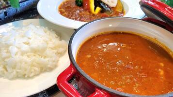 A table with a pot of soup and a plate of rice.