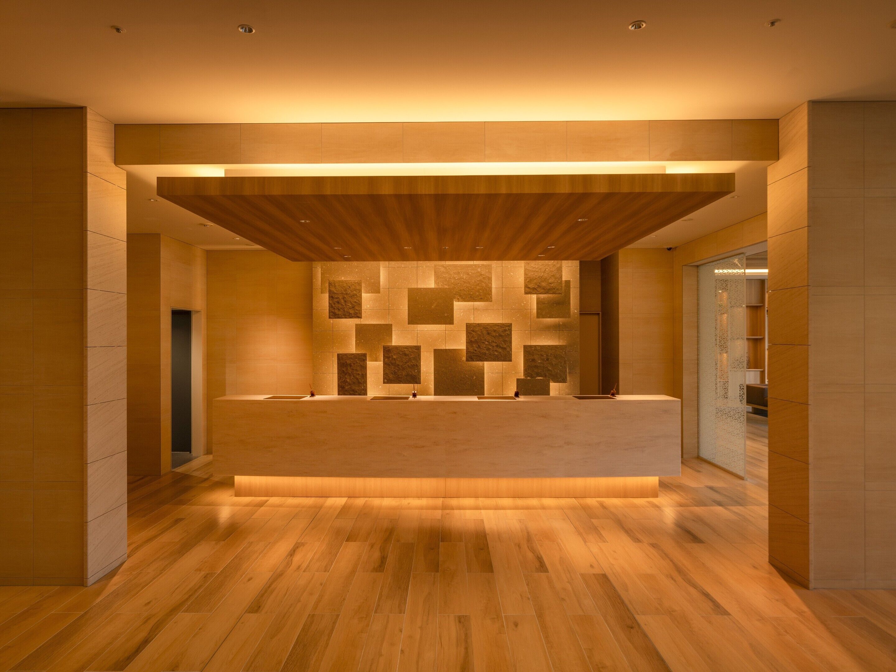 A modern reception area with a wooden reception desk, a patterned wall, and a wooden floor.
