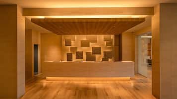 A modern reception area with a wooden reception desk, a patterned wall, and a wooden floor.