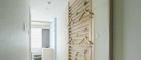 A hallway with a mirror, wooden hanger rack, and a bench with shoe storage.