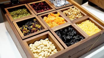 Une boîte en bois compartimentée contenant divers fruits secs et noix.