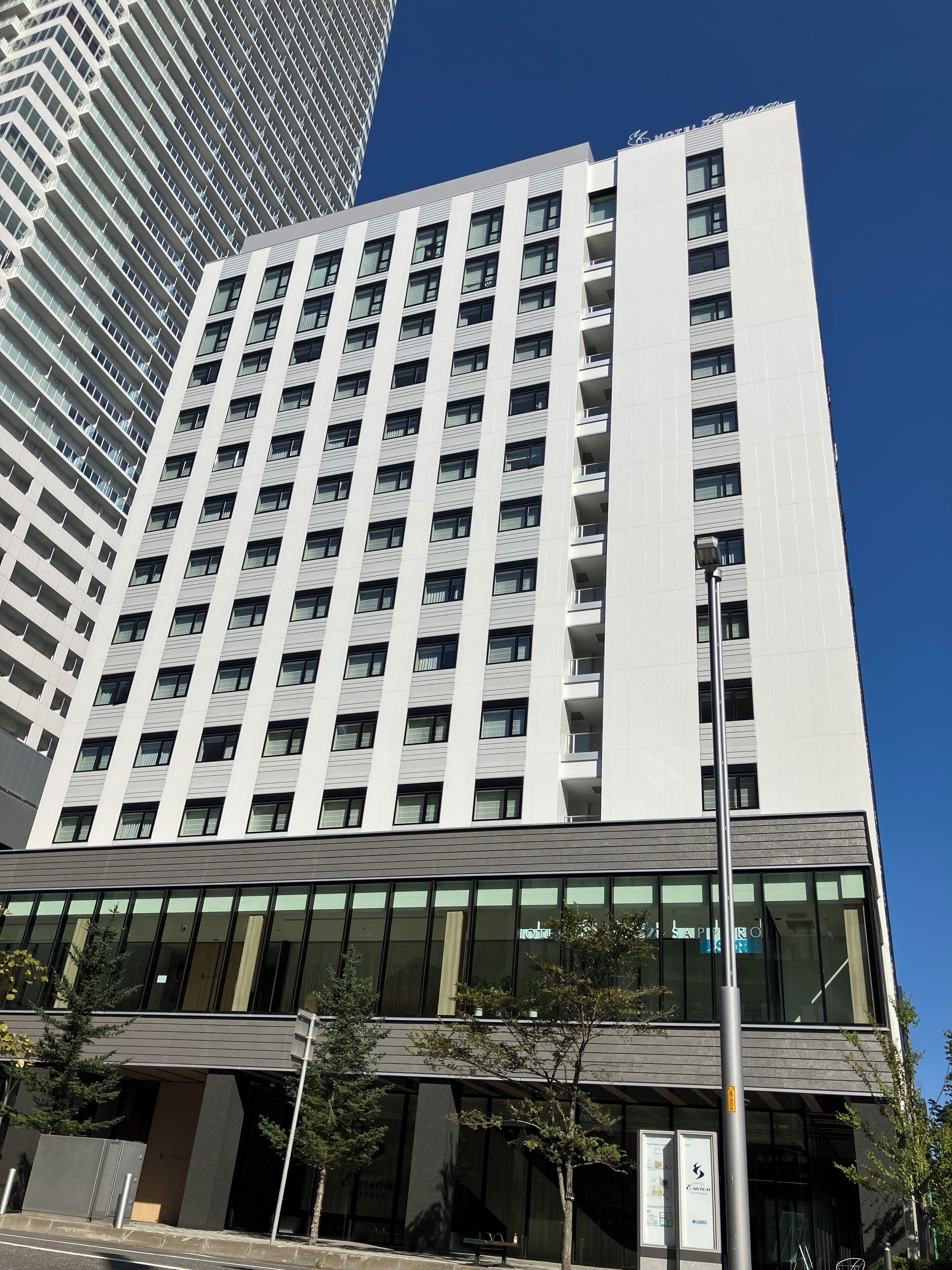 A modern hotel building with a prominent glass facade, multiple floors, and a clear sky.