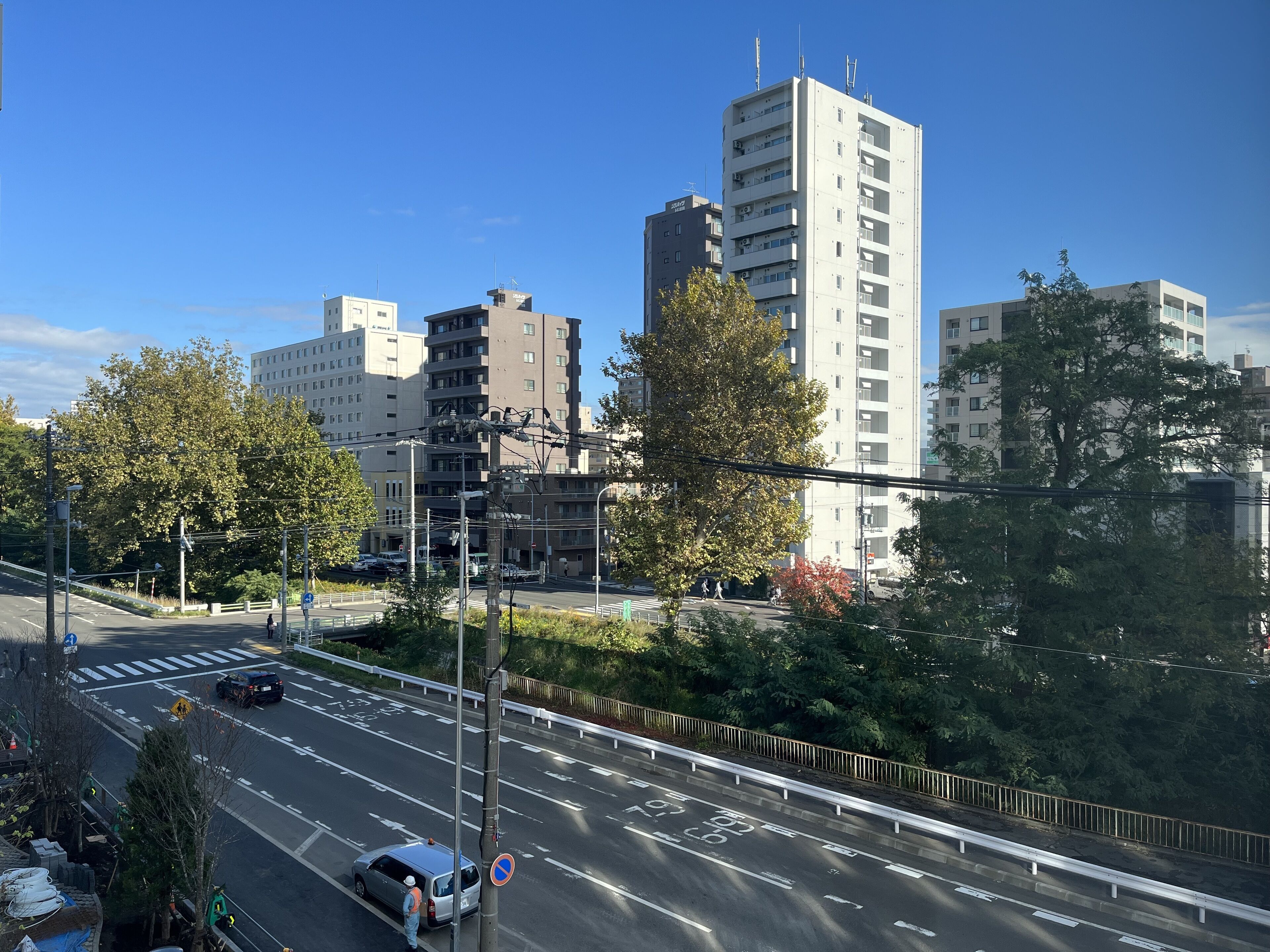 Un edificio de varios pisos con un diseño arquitectónico moderno, rodeado de árboles y un cielo despejado.