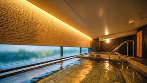 Zona de spa con un amplio ventanal, suelo de piedra y techo de madera.