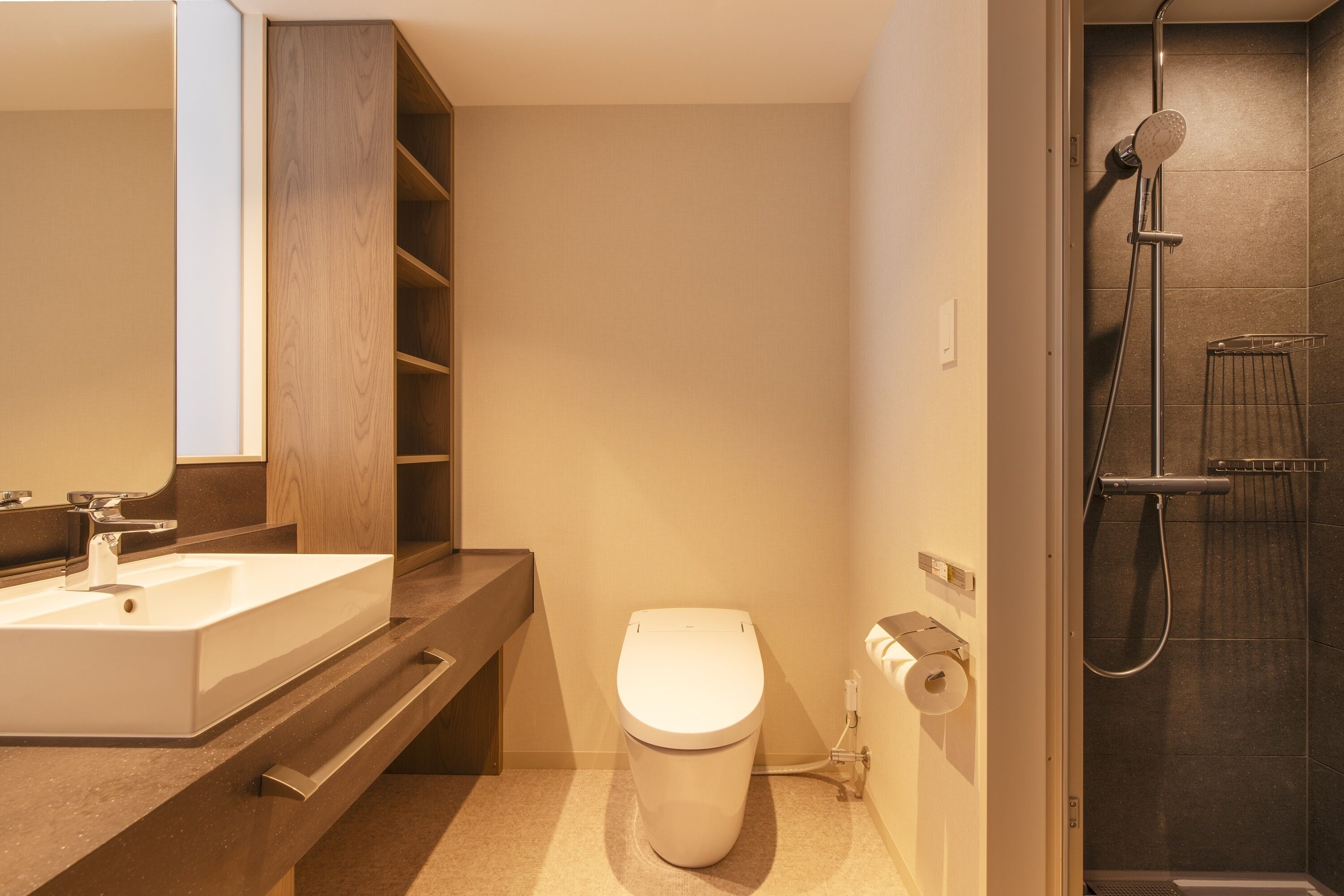 A modern bathroom with a large sink, toilet, and shower.