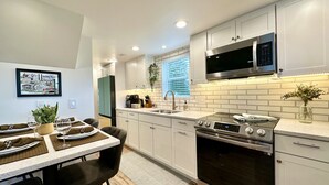 Une cuisine moderne avec des armoires blanches, une cuisinière en acier inoxydable et un four à micro-ondes.