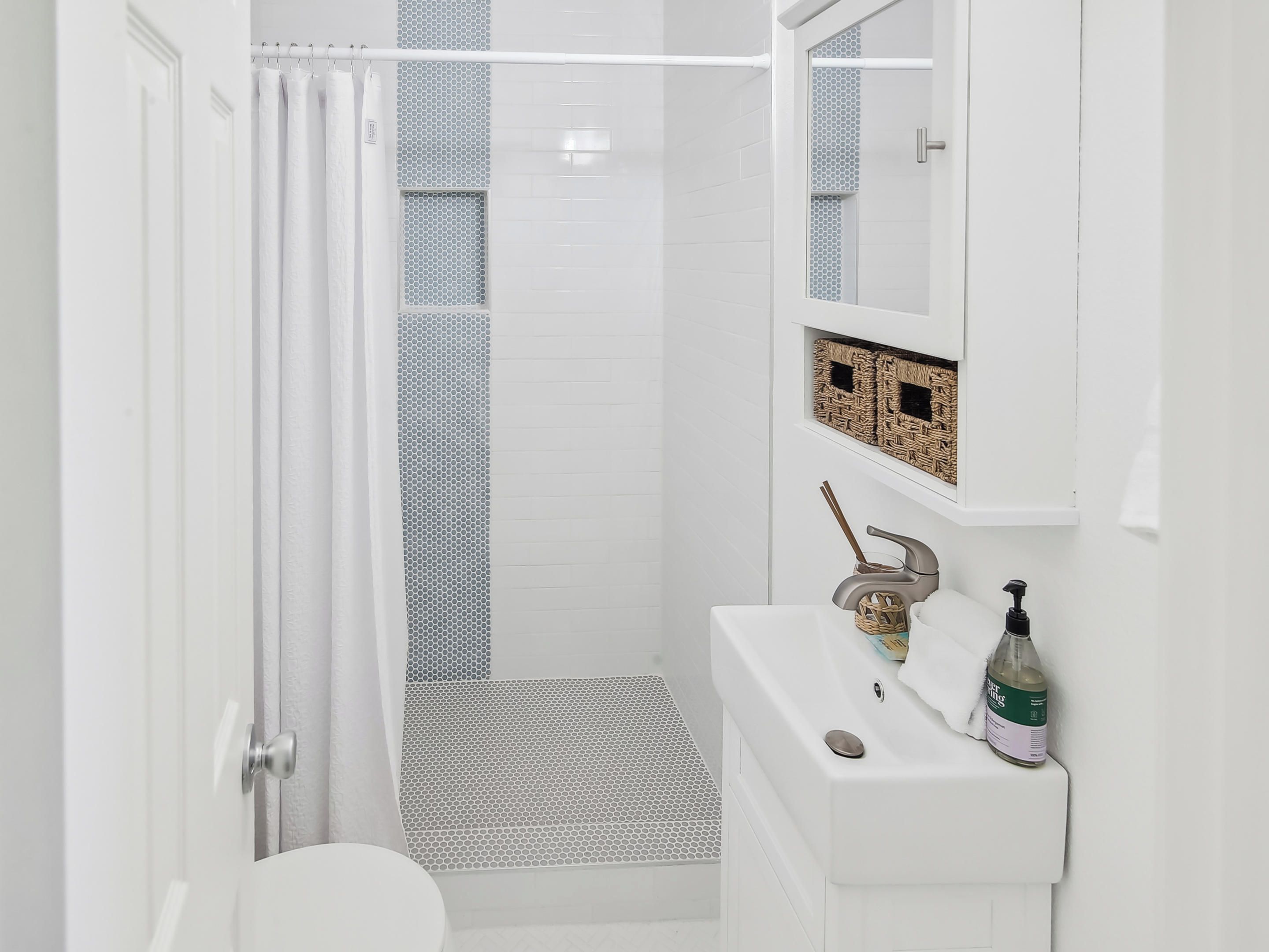 A modern bathroom with a shower, toilet, and sink.