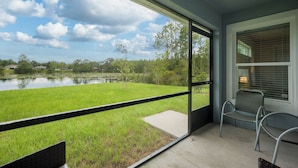 Un balcón con vistas a un lago, una zona verde y una silla.