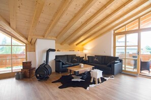 Ein gemütliches Wohnzimmer mit Kamin, einer Couch, einem Couchtisch und einem großen Fenster.