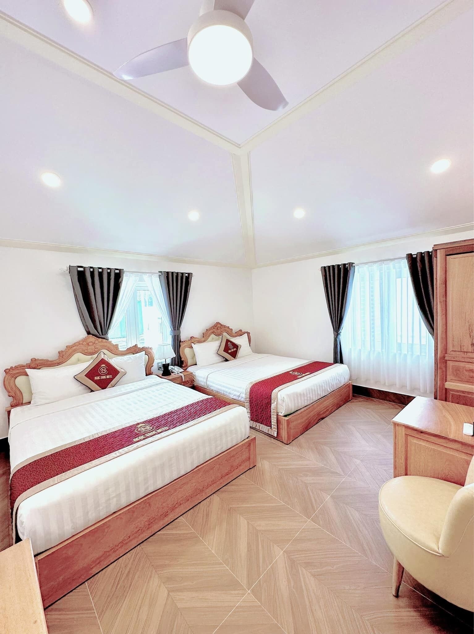 Habitación de hotel con dos camas, un ventilador de techo y un armario de madera.