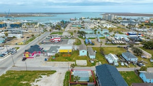 An aerial view of a coastal town with a marina, various buildings, and a prominent pink ice cream shop. - Tranquil Cove by Jackson Mountain Rentals (Port Aransas)