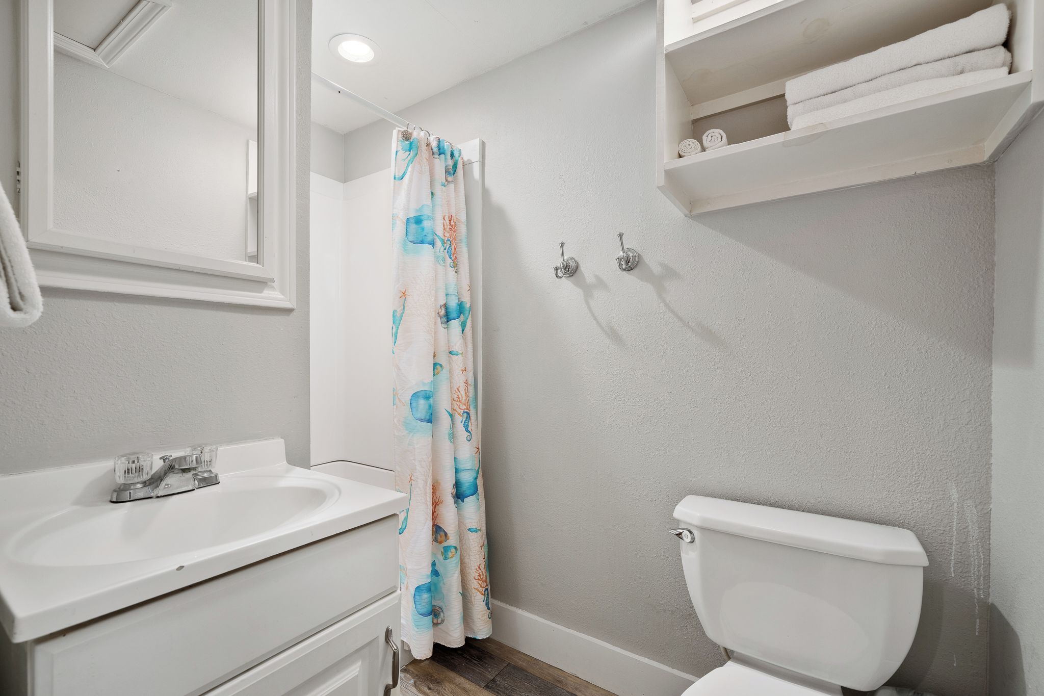 A bathroom with a white sink, toilet, and shower curtain with a blue and orange pattern.
