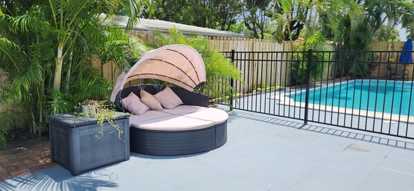 A poolside area with a wicker chair and a small planter. - 10 minutes to the beach, Cozy Family Stay · Near everything · Free Parking (Oakland Park)