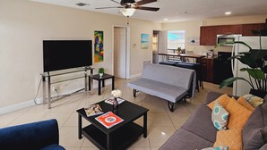 Una sala de estar con sofá, mesa de centro, televisor y ventilador de techo.