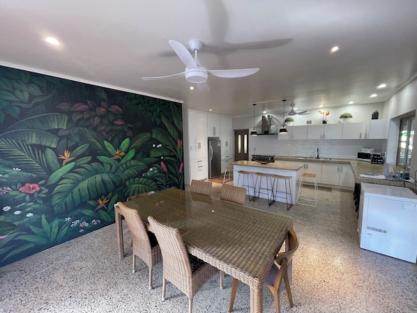 A modern kitchen with white cabinets, a central island, and a ceiling fan. - Villa Honey Rose Private Pool & unlimited WIFI (Rarotonga)