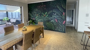 Un comedor con un mural de temática tropical, muebles de mimbre y vistas al exterior.