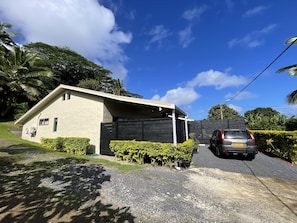 Une maison à deux étages avec un garage, entourée de verdure et sous un ciel bleu azur.