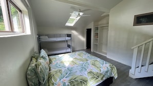 Habitación tipo dormitorio con literas, ventilador de techo, tragaluz y vestidor.