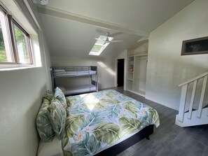 Une chambre de type dortoir avec des lits superposés, un ventilateur de plafond, un puits de lumière et un dressing.