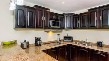 A kitchen with dark wood cabinets, a granite countertop, a built-in microwave, a coffee maker, and a toaster.