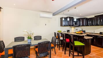 A dining area with a table and chairs, a kitchen with dark cabinets, and a ceiling fan.