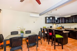 A dining area with a table and chairs, a kitchen with dark cabinets, and a ceiling fan. - Coco Sunset Hills 52 (Coco)