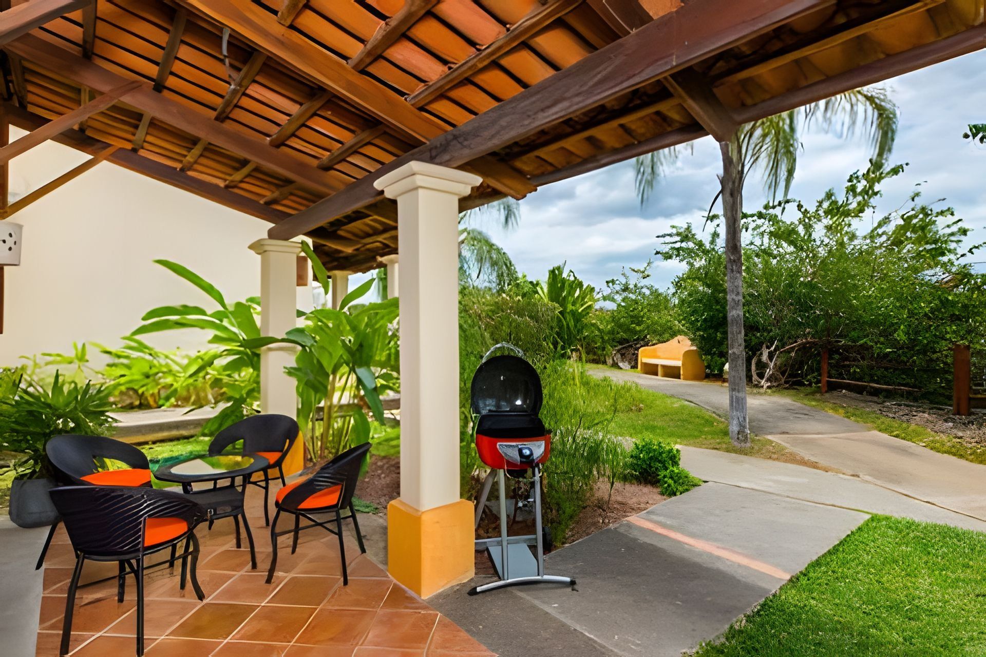 An outdoor patio with a grill, chairs, and a table.