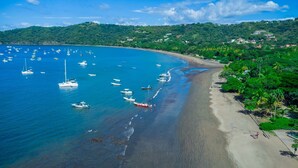 A coastal beach with boats, a sandy shore, and lush greenery. - Coco Sunset Hills 52 (Coco)
