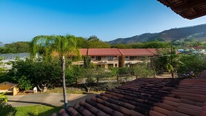 A building with a red roof, surrounded by greenery and hills. - Coco Sunset Hills 52 (Coco)