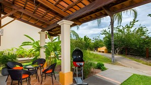Un patio exterior con una parrilla, sillas y una mesa.