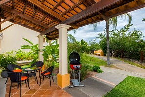 Un patio exterior con una parrilla, sillas y una mesa.
