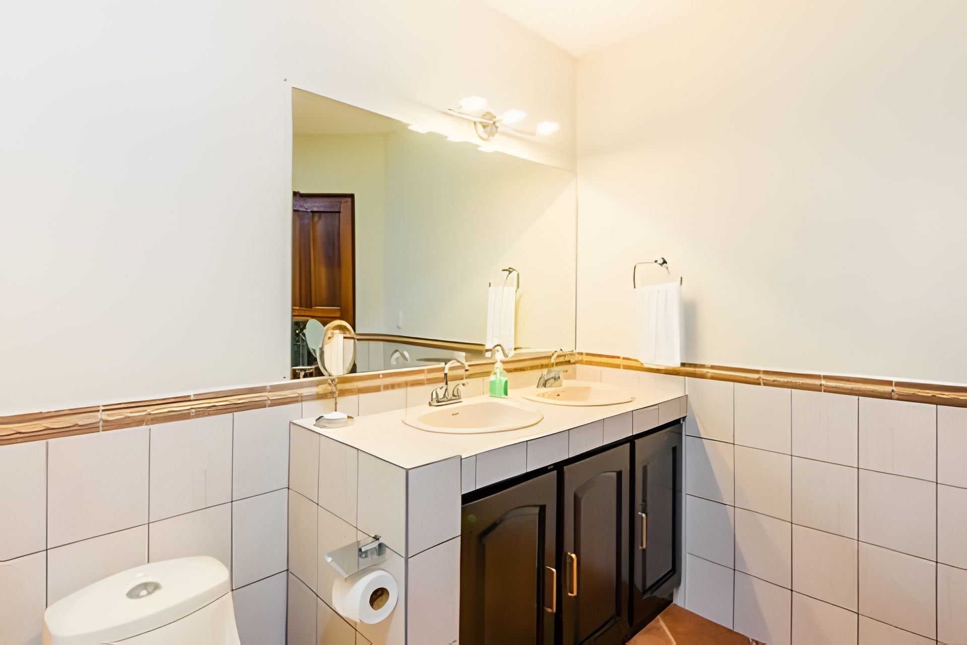 Une salle de bain avec deux lavabos, des toilettes, un miroir et un porte-serviettes.