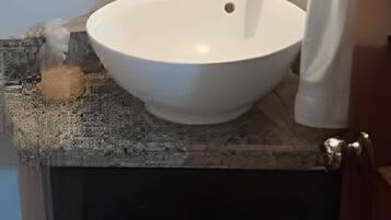 A bathroom with a round mirror, a white sink, and dark cabinets.
