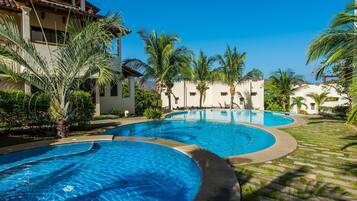 A resort with multiple swimming pools, palm trees, and a clear blue sky.