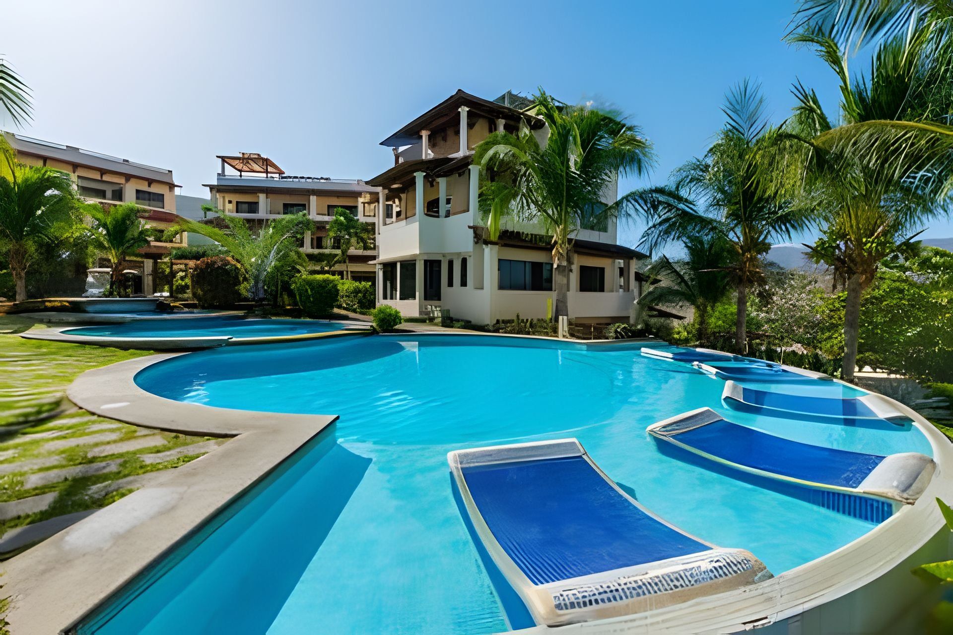 A resort with multiple swimming pools, palm trees, and modern buildings.