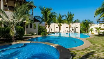 Ein Resort mit mehreren Pools, Palmen und blauem Himmel.