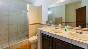 Un baño moderno con cabina de ducha de vidrio, inodoro, lavabo con espejo y tocador.